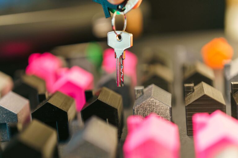 Llave de una vivienda sobre maquetas de casas y términos del glosario de educación hipotecaria