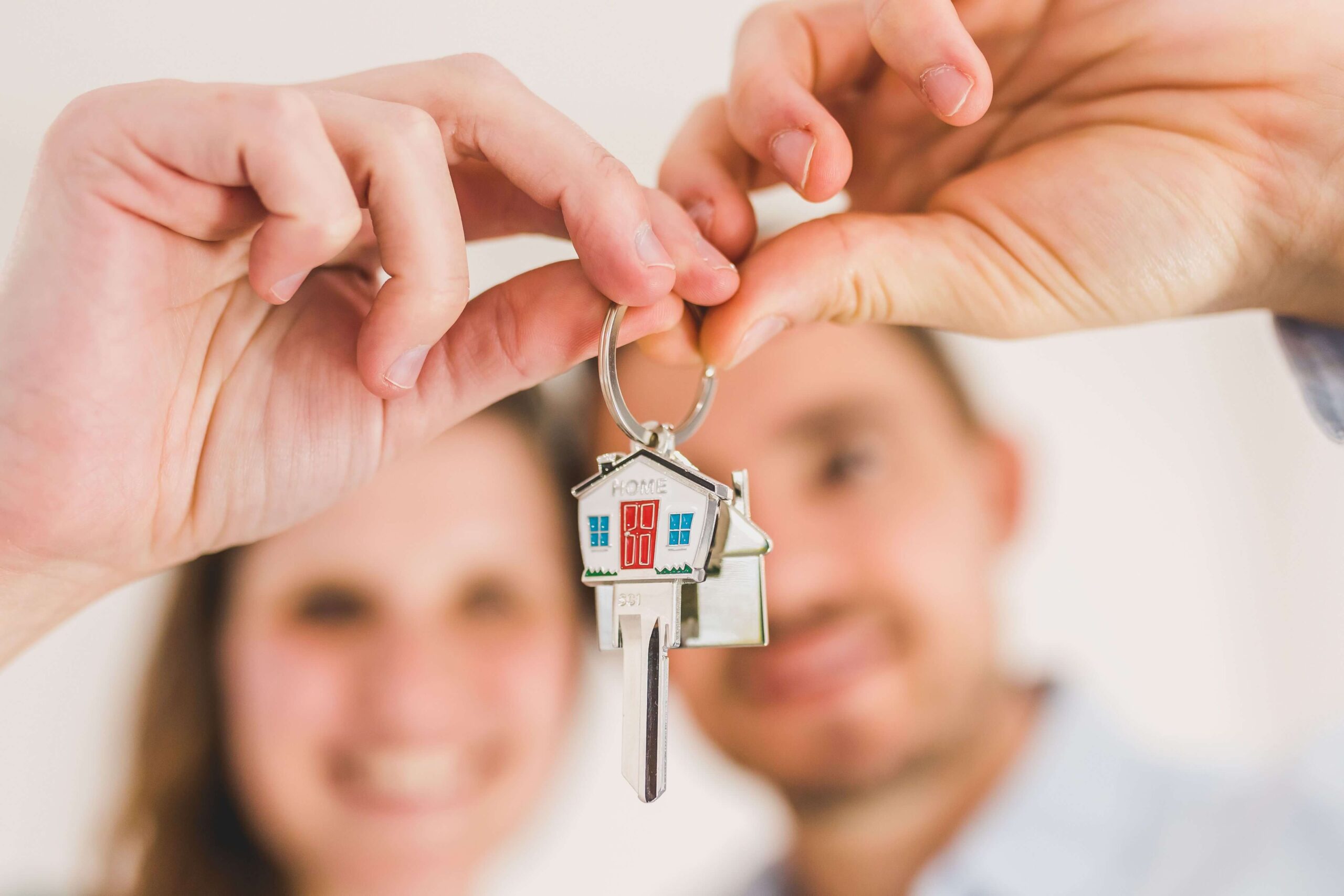 Pareja feliz celebrando la concesión de su hipoteca al recibir las llaves de su nueva casa